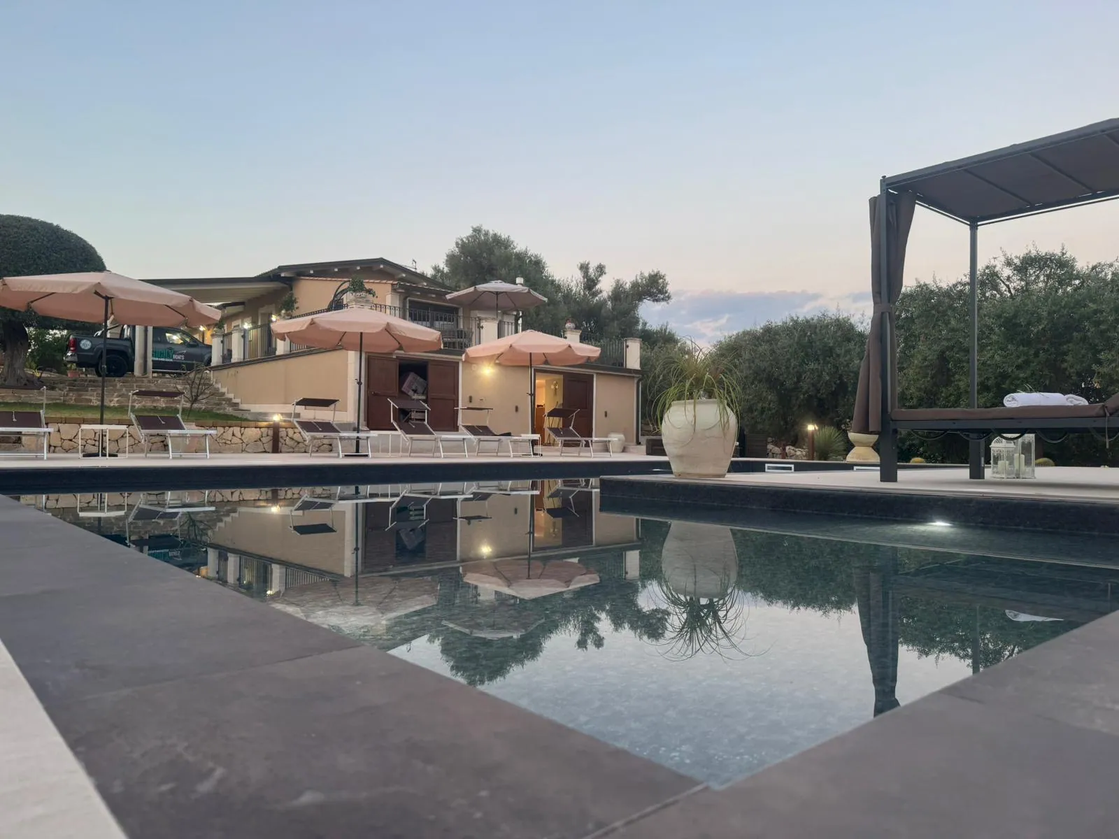 Villa Badessa al tramonto, con la piscina che riflette la casa e il cielo